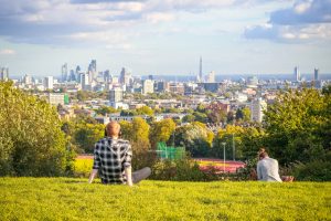 London, UK - October 5, 2017 - Back view of tourists looking over London city skyline from Parliament Hill in Hampstead Heath